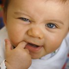 High angle of a baby girl sitting on a step looking up to the viewer with her hand her mouth