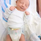 Family looking down at baby boy (0-3 months) in christening gown