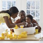 Grandmother's hands bathing granddaughter (9-12 months) in sink,