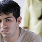 Man holding newspaper looking at woman on sofa using laptop