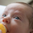 Little baby with bottle in white bed