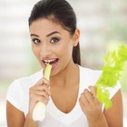 Woman holding bananas in produce aisle of supermarket, side view