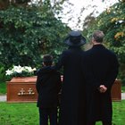 portrait of a young couple and their son standing over a coffin