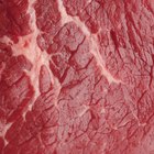 Butcher cutting beef meat on a wooden table