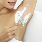 Woman shaving armpit in bathroom