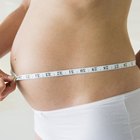 Young pregnant woman in jeans holding stomach