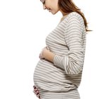 Young pregnant woman drinks tea with sweets at kitchen