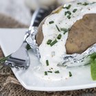 close-up of a baked potato served with sour cream in foil