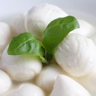 Small mozzarella balls in a white dish with liquid.