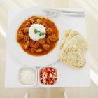 Elevated view of white rice and curry served with salad and bread