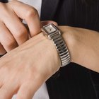 Mid adult man standing at street, looking at watch