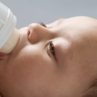 Little baby with bottle in white bed