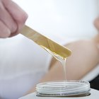 Young woman on treatment table, masseuse pouring lotion into palm