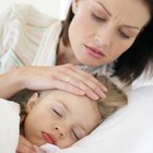 High angle view of a baby girl with a doll lying in bed