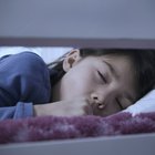 woman talking on the telephone and looking at thermometer while boy (10-12) sleeps in bed