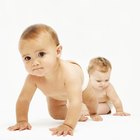 Female baby (6-9 months) crawling towards camera as another baby playing behind