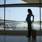 Pregnant woman pulling a suitcase inside airport