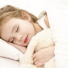 Smiling toddler boy standing atop hotel bed