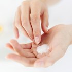 Close-up of a woman's hand applying lotion to her shoulder