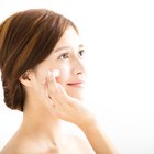 Mother applying sun lotion to daughter's (7-9) face, outdoors