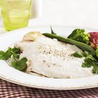 raw sliced steak of sturgeon fish with greens, lemon,