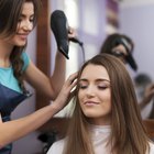Female hairdresser using hairbrush and hair dryer