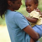 Pregnant woman holding crying girl while talking on telephone