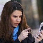 Couple laying in bed looking at their smart phones.