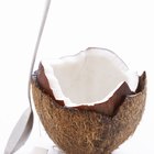 Opened coconut with a straw on summer beach.