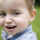 High angle of a baby girl sitting on a step looking up to the viewer with her hand her mouth