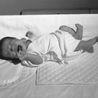 Close-up of a baby boy holding the railing of a crib