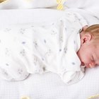 Petit bébé avec un biberon dans un lit blanc