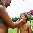 Mother applying sun lotion to daughter's (7-9) face, outdoors
