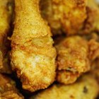 Baked chicken wings with sesame seeds and sweet chili sauce on white wooden board.