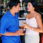 close-up of a woman holding a glass of wine and smiling at a man