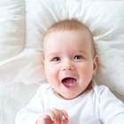 Mother holding baby girl's (6-9 months) legs, smiling