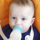 baby with small bottle in bed