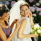 Young woman putting flower in bride's hair, smiling