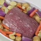 Ingredients for meat broth in pan on wooden table: beef, onion, carrot, celery, parsley and spices.