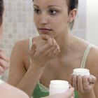 Close-up of a woman's hand applying lotion to her shoulder