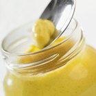 Jar of mustard and spoon with mustard above jar, extreme close-up, part of