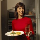 Pregnant female choosing between broccoli in glass bowl and vitamins