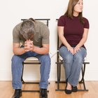 Couple sitting apart on bed, night