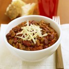 Beef chili with beans and cheese topping in a bowl on a table