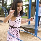 Five children (7-11) running with plastic hoops in park (surface level)