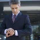 Mid adult man standing at street, looking at watch