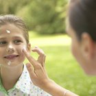 Mother applying sun cream to son's (8-10) face, smiling, close-up