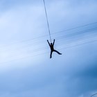 Man bungee jumping, seen against blue sky, view from below
