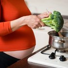 Pregnant young woman stretching by desk, eyes closed