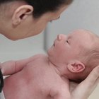 Side profile of a female doctor examining a baby boy with a stethoscope